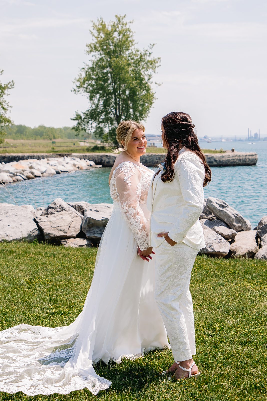 Brides holding hands by the water at The Terrace at Delaware Park